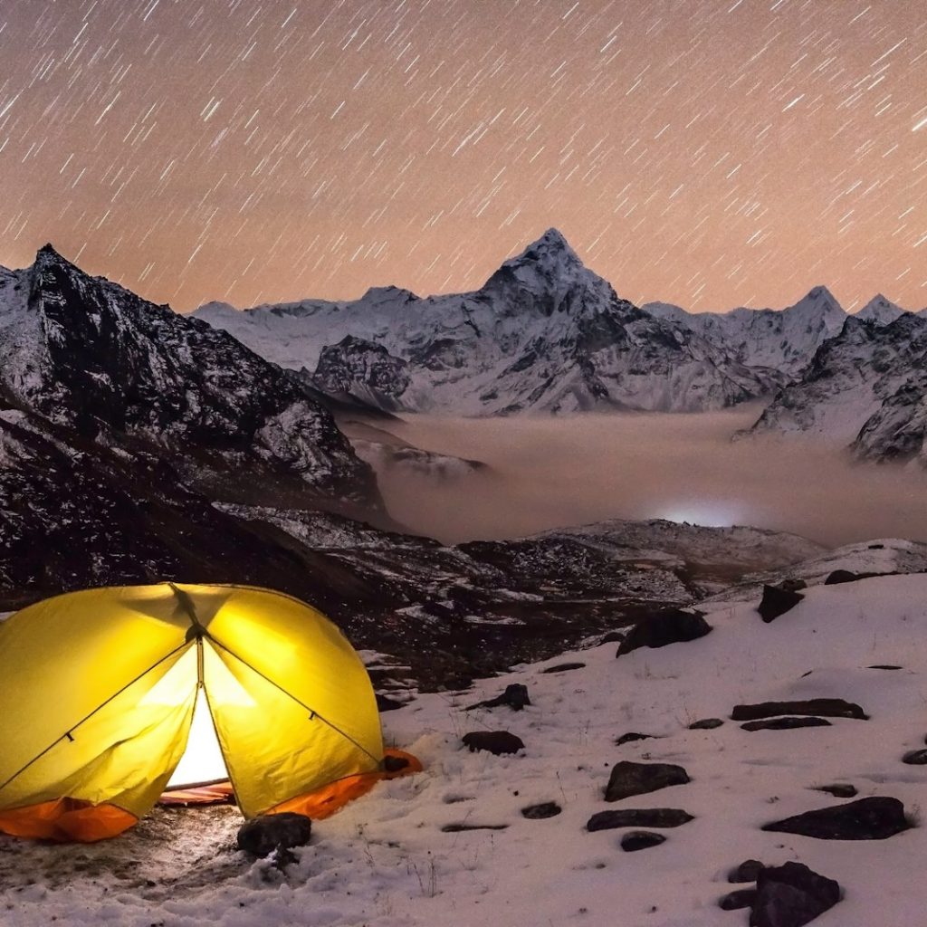 a tent pitched up on a snowy mountain at night