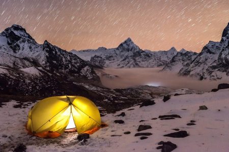 a tent pitched up on a snowy mountain at night