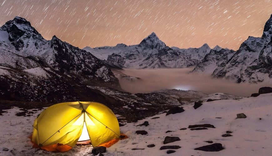 a tent pitched up on a snowy mountain at night