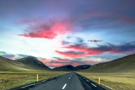 gray concrete road near green grass field and mountain under gray clouds